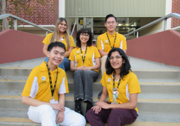 Five student peer health educators sitting on steps of Student Health Center